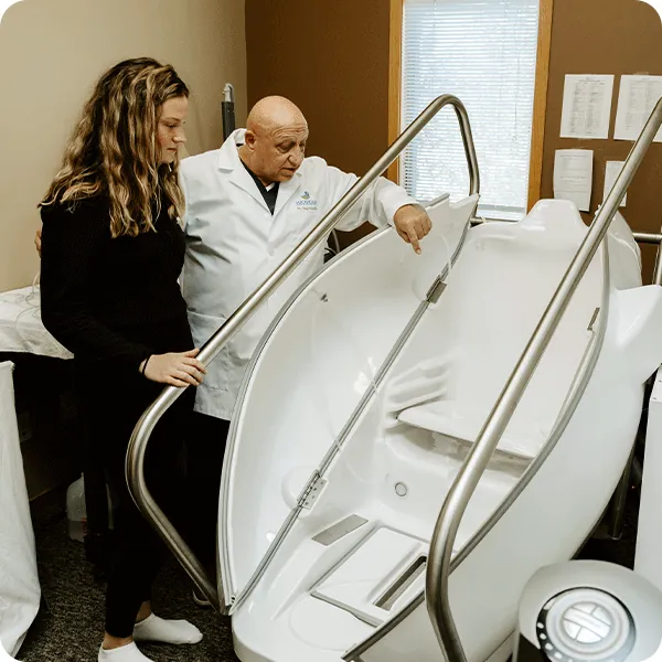 Doctor Tony instructs female patient on the HOCATT Hyperthermic Ozone chamber