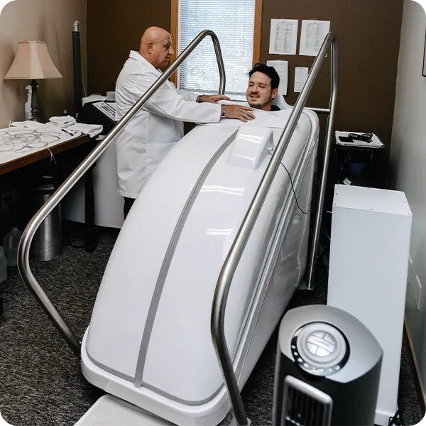 Doctor Tony monitors male patient sitting in the HOCATT Hyperthermia box